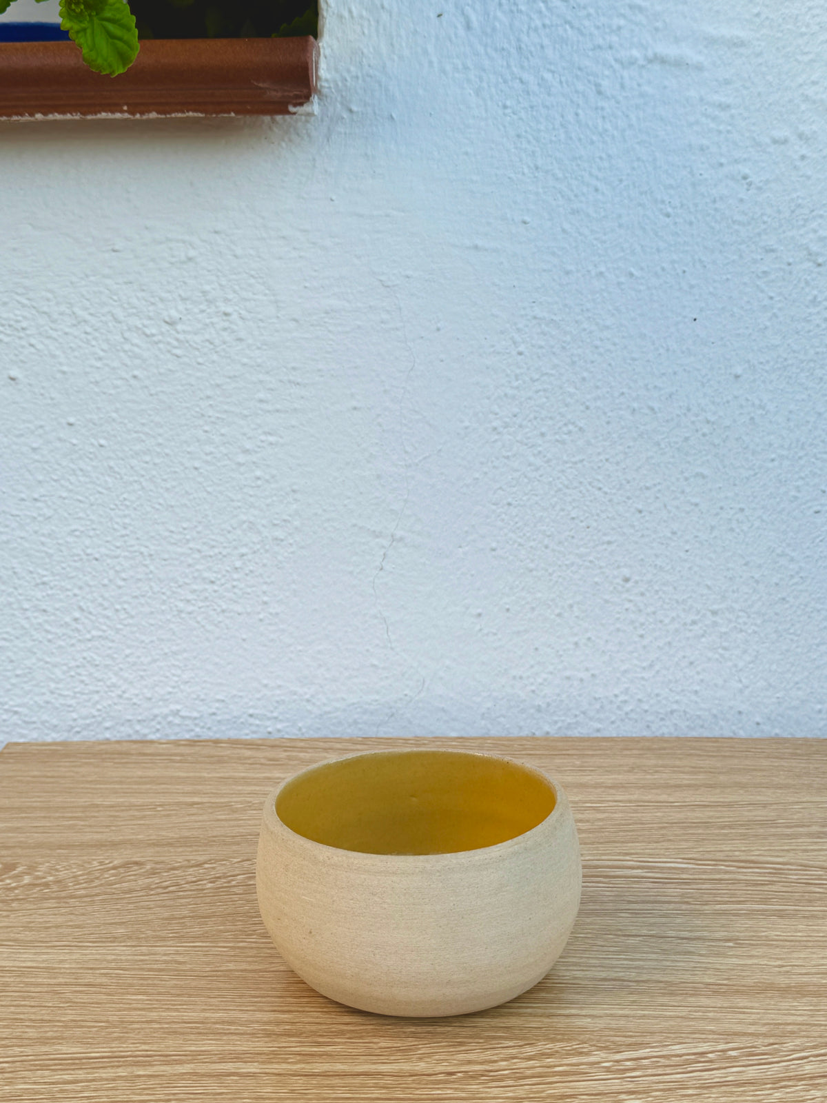 Small ceramic bowl with mustard yellow interior glaze on wooden table